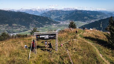 A person rings a bell, behind which you can see the mountains around Zell am See-Kaprun | © Zell am See-Kaprun Tourismus